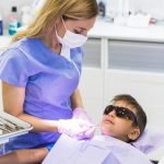 female-dentist-checking-boy-s-teeth-with-dental-mirror_23-2147905941